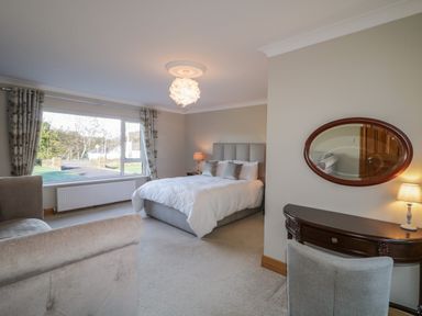 A bedroom with a bed sofa window with curtains lamp and dressing table at Nellys House in Gortahork County Donegal