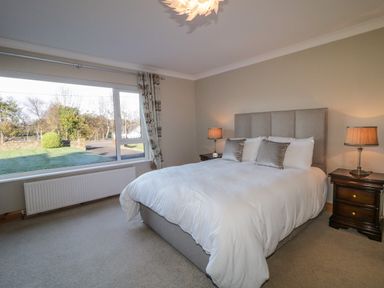 A bedroom with a bed two bedside tables two table lamps and a large window at Nellys House in Gortahork County Donegal