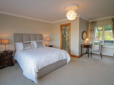 A bedroom with a bed two nightstands with lamps a desk a chair and a window at Nelly's House in Gortahork County Donegal