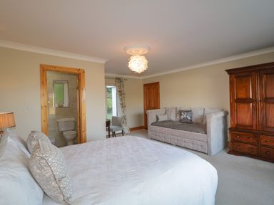A bedroom with a large bed a sofa and a wooden wardrobe at Nelly's House in Gortahork County Donegal