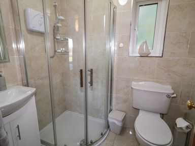 A bathroom with a shower enclosure a toilet a sink and a small window at Nelly's House in Gortahork County Donegal
