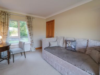 A sitting room with a sofa a chair a wooden table and curtains at Nellys House in Gortahork County Donegal