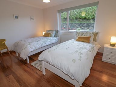 A bedroom with two single beds side by side a window with a view outside and a nightstand with a lamp at Nelly's House in Gortahork County Donegal