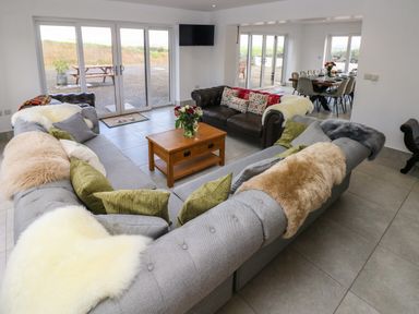 A living room with sofas pillows and a wooden coffee table connected to a dining area at Little Pale Near Whitland