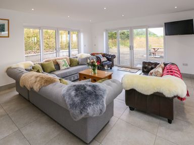 A sitting room with sofas, a coffee table, and large windows at Little Pale Near Whitland