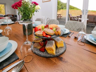 A dining table set with plates bowls glasses and a two-tier tray of pastries and fruit at Little Pale Near Whitland