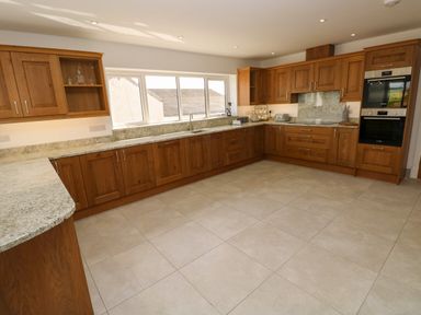 A kitchen with wooden cabinets granite countertops double ovens and a large window at Little Pale Near Whitland
