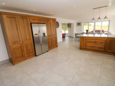 A kitchen with wooden cabinets a stainless steel refrigerator and a countertop with pendant lights at Little Pale Near Whitland