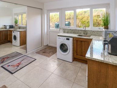 A utility room with washing machine microwave mirrored closet and granite countertops at Little Pale Near Whitland