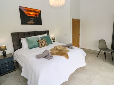 A bedroom with a bed with pillows and towels and a chair near a wooden door at Little Pale Near Whitland