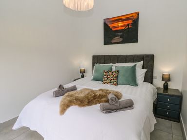 A bedroom with a double bed pillows rolled towels bedside tables and lamps at Little Pale Near Whitland