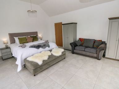 A bedroom with a bed a sofa two wardrobes and a bench at Little Pale Near Whitland