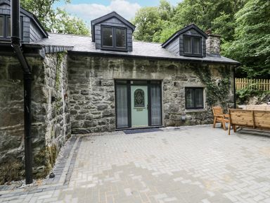 A house with a stone wall and patio area at Frongoch Old Power House in Dolgellau