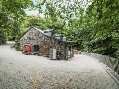 An outdoor area with a stone building and a paved road at Frongoch Old Power House in Dolgellau