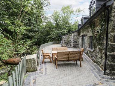 An outdoor patio with wooden furniture at Frongoch Old Power House in Dolgellau