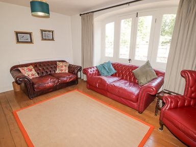 A sitting room with two leather sofas a leather armchair and a large window at Clearbrook Lodge in Llanarthney nr Llandeilo Carmarthenshire