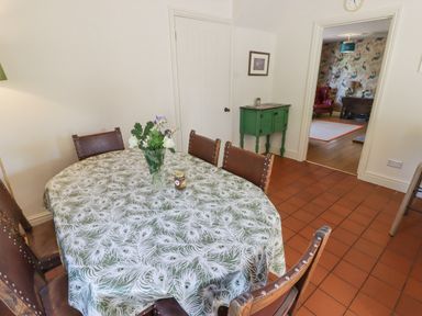 A dining room with a table covered by a peacock feather patterned tablecloth and six brown chairs at Clearbrook Lodge in Llanarthney nr Llandeilo Carmarthenshire
