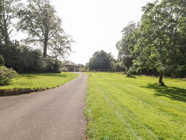 A driveway leading to a house surrounded by grass and trees at Clearbrook Lodge in Llanarthney nr Llandeilo Carmarthenshire