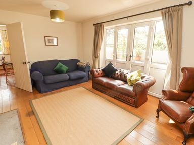 A living room with two sofas one blue and one brown leather and an armchair near a window with curtains at Meadow Cottage in Llanarthney nr Llandeilo Carmarthenshire
