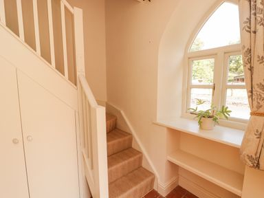 A staircase with beige carpet next to a built-in window seat with a potted plant at Meadow Cottage in Llanarthney nr Llandeilo Carmarthenshire