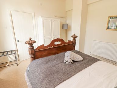 A bedroom with a wooden bed with towels on it and a white wardrobe in the corner at Meadow Cottage in Llanarthney nr Llandeilo Carmarthenshire
