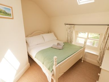 A bedroom with a double bed green blanket and towels by a window at Meadow Cottage in Llanarthney nr Llandeilo Carmarthenshire