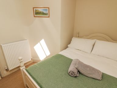 A bedroom with a bed covered with a green blanket and two folded towels on top at Meadow Cottage in Llanarthney nr Llandeilo Carmarthenshire