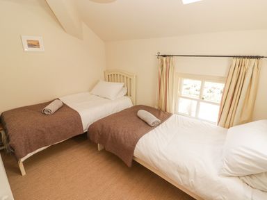 A bedroom with two single beds with brown blankets by a window at Meadow Cottage in Llanarthney nr Llandeilo Carmarthenshire