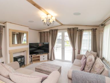 A living room with sofas a television and a fireplace at Drake 11 in Cayton Bay