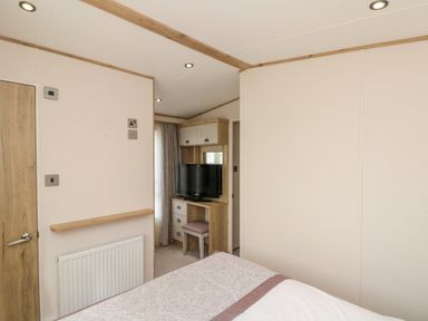 A bedroom with a bed a wall-mounted radiator a wooden door and a corner with a tv on a wooden desk at Drake 11 in Cayton Bay