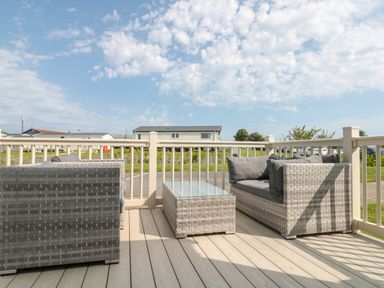 An outdoor deck with wicker sofas and a glass top table at Drake 11 in Cayton Bay