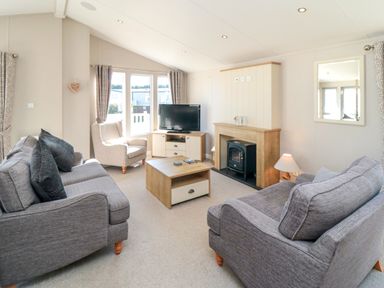 A living room with two grey sofas a beige armchair a wooden coffee table a fireplace and a television at 28 Finch in Cayton Bay