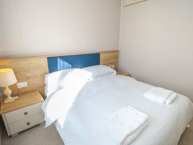 A bedroom with a double bed two bedside tables two lamps and folded towels on the bed at 28 Finch in Cayton Bay