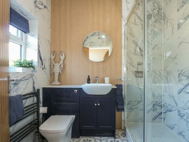 A bathroom with a toilet sink cabinet and shower at Swn Y Wylan Red Wharf Bay near Benllech