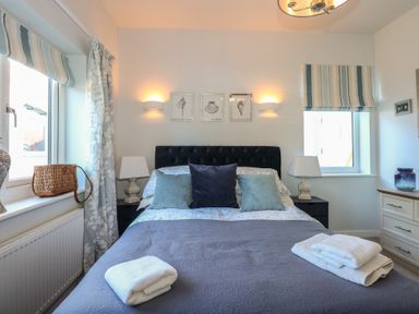A bedroom with a bed with pillows and folded towels placed on top at Swn Y Wylan Red Wharf Bay near Benllech