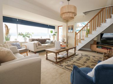 A living room with sofas a wooden coffee table and stairs near a television at Swn Y Wylan Red Wharf Bay near Benllech