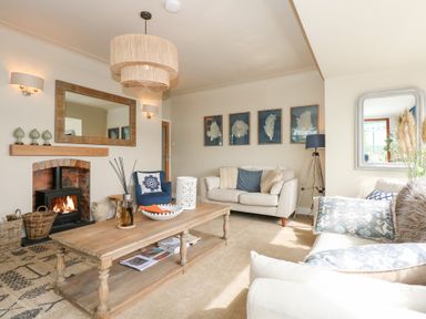 A living room with sofas a wooden coffee table a fireplace and framed artworks on the wall at Swn Y Wylan Red Wharf Bay near Benllech