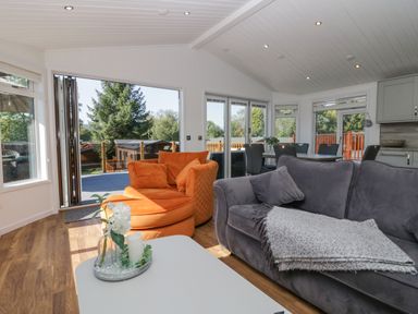 A living room with orange and gray sofas and a white coffee table at Lakeland View Ambleside 86 White Cross Bay near Windermere