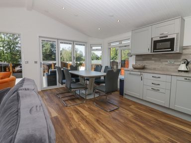A kitchen and dining area with a table and chairs near large windows at Lakeland View Ambleside 86 White Cross Bay near Windermere