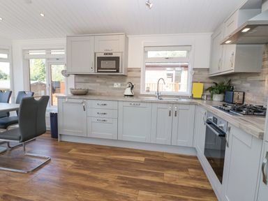A kitchen with gray cabinets stainless steel oven and microwave wooden floor and dining chairs at Lakeland View Ambleside 86 White Cross Bay near Windermere