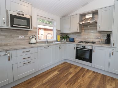 A kitchen with grey cabinets wooden floor and stainless steel appliances at Lakeland View Ambleside 86 White Cross Bay near Windermere