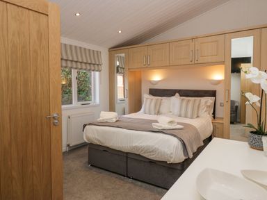 A bedroom with a double bed and built in wooden wardrobes at Lakeland View Ambleside 86 White Cross Bay near Windermere