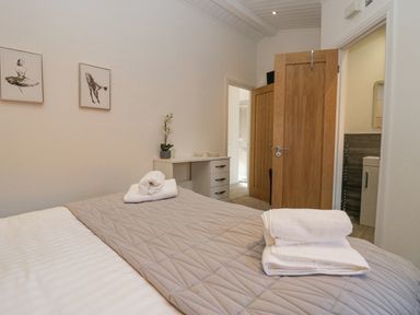 A bedroom with a bed folded towels a desk with a plant and two framed pictures on the wall at Lakeland View Ambleside 86 White Cross Bay near Windermere