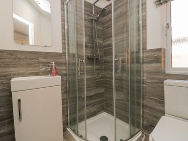 A bathroom with a corner glass shower enclosure a white sink a mirror and a toilet at Lakeland View Ambleside 86 White Cross Bay near Windermere