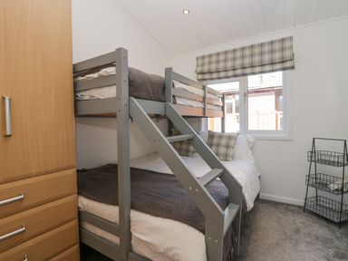 A bedroom with a bunk bed a wardrobe and a window with a patterned blind at Lakeland View Ambleside 86 White Cross Bay near Windermere