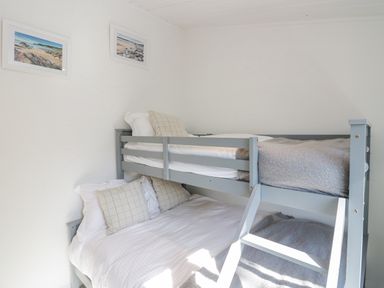 A bedroom with a grey bunk bed with pillows and blankets and framed pictures on the wall at Lakeland View Ambleside 86 White Cross Bay near Windermere