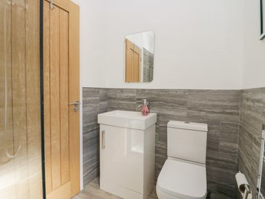 A bathroom with a wooden door sink with soap dispenser mirror and toilet at Lakeland View Ambleside 86 White Cross Bay near Windermere