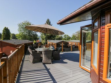 A balcony with wicker chairs and a round glass table under an umbrella at Lakeland View Ambleside 86 White Cross Bay near Windermere