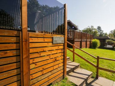 Wooden deck with glass panels and stairs leading to a grassy area at Lakeland View Ambleside 86 White Cross Bay near Windermere