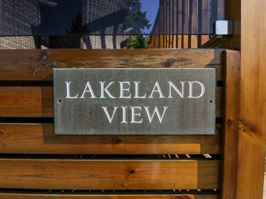 A wooden fence with a metal plaque that reads Lakeland View at Lakeland View Ambleside 86 White Cross Bay near Windermere